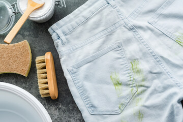 Dirty stains of fresh green grass on blue jeans. Natural cleaning products. Zero waste concept. top...