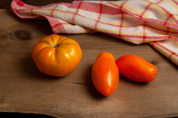 Yellow tomatoes and red towel on wooden background..