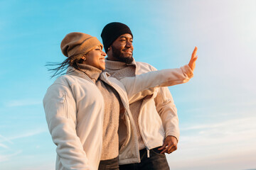 cheerful couple reaching destination and waving hand against blu sky at sunset. Love, hiking and...