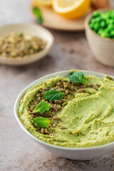Hummus made of chickpeas, fresh green peas and mint, sprinkled with seeds