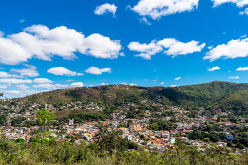 Partial view of the city of Sabará, Brazil. Streets, bridge, mountain, trees and blue sky with clouds.