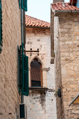 Beautiful window in Gothic building. View among buildings in old Mediterranean city. Vertical orientation