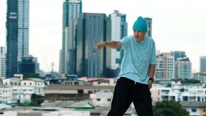 Skilled caucasian B-boy dancer practicing street dancing at rooftop with city sites or urban....