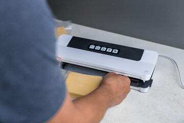 man vacuum-packing cheese with a vacuum cleaner