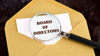 Business concept. Text BOARD OF DIRECTORS on a white sheet of paper through a magnifying glass on the background of a postal envelope