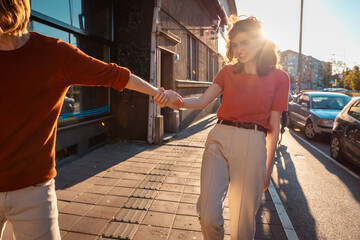 Young couple, Caucasian man and woman, holding hands, are running down the street. Concept of...