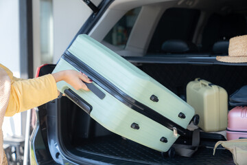 The young woman is carrying her luggage onto the back of the vehicle in preparation for her journey