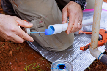 An experienced plumber seals pvc plastic pipes with glue before gluing them together