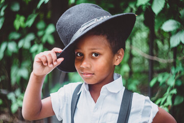 close-up of a boy in the style of the 20s looking seriously at the camera, raising his hat