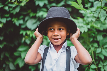 the boy smiles and puts a hat on his head