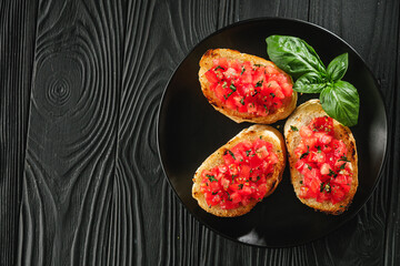 delicious Italian bruschetta with tomatoes on a black wooden rustic background