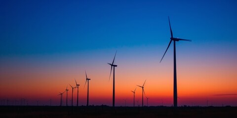 Obraz premium Large wind turbines against the backdrop of a setting sun.