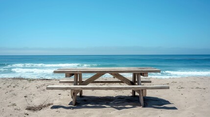 Wooden picnic table on sandy beach with ocean view.
