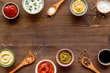 Set of sauces in bowls with spices in spoons and ingredients, top view