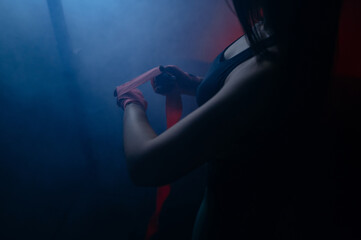 Woman is wrapping hands with pink boxing wraps. Isolated on black with red nails. Strong hand and fist, ready for fight and active exercise.