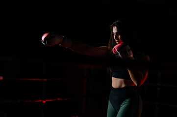 young sexy girl boxer doing boxing with shadow inside the boxing ring. Boxer practices punches in...