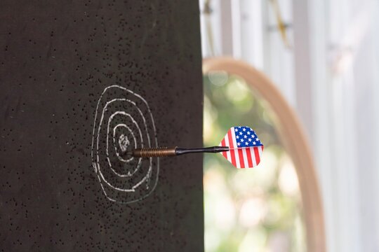 An American flag dart hits the center of a dartboard.