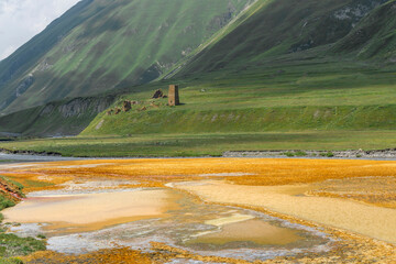 Colorful colors of mineral salts and water in the river bed. Fortress tower on thr hill