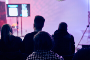 An audience with people in the background is a screen with a presentation. A rear view of...