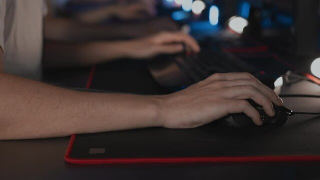 Skill Close up player's hands use professional gaming mouse and PC keyboard with RGB lighting, mat. E-sport tournament with cyber team in computer club. Gamers play video game. Strategy shooter