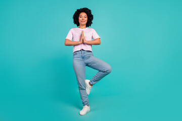 Photo of dreaming girl in pink t shirt and jeans stylish garment stand one leg meditation pose isolated on cyan color background