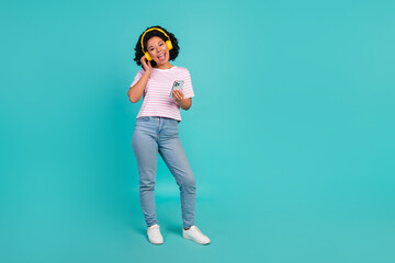 Photo of funny youngster girl with curly hairstyle listen music her new bluetooth headphones choose...