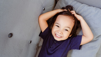 happy Asian child holding his head and hair