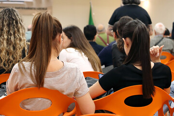 Two young girls with ponytails sitting back to back during a conference