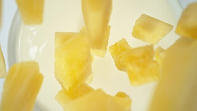 Super Slow Motion of Falling Pineapple Pieces into Cream. Filmed on High Speed Cinema Camera, 1000fps, Placed on High Speed Cine Bot. Camera in Motion, Following Objects.