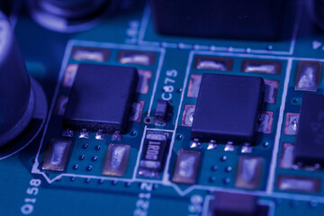 Green circuit board with a black integrated circuit chip and various small electronic components