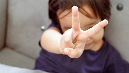 Portrait of child boy showing victory hand sign