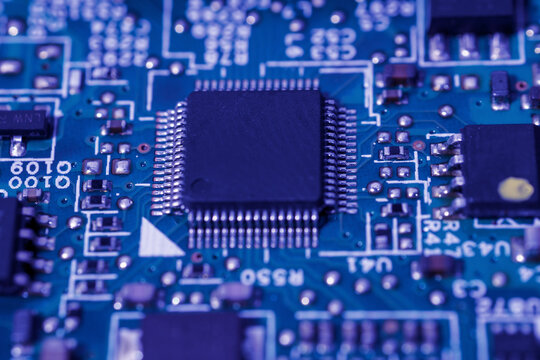 Green circuit board with a black integrated circuit chip and various small electronic components