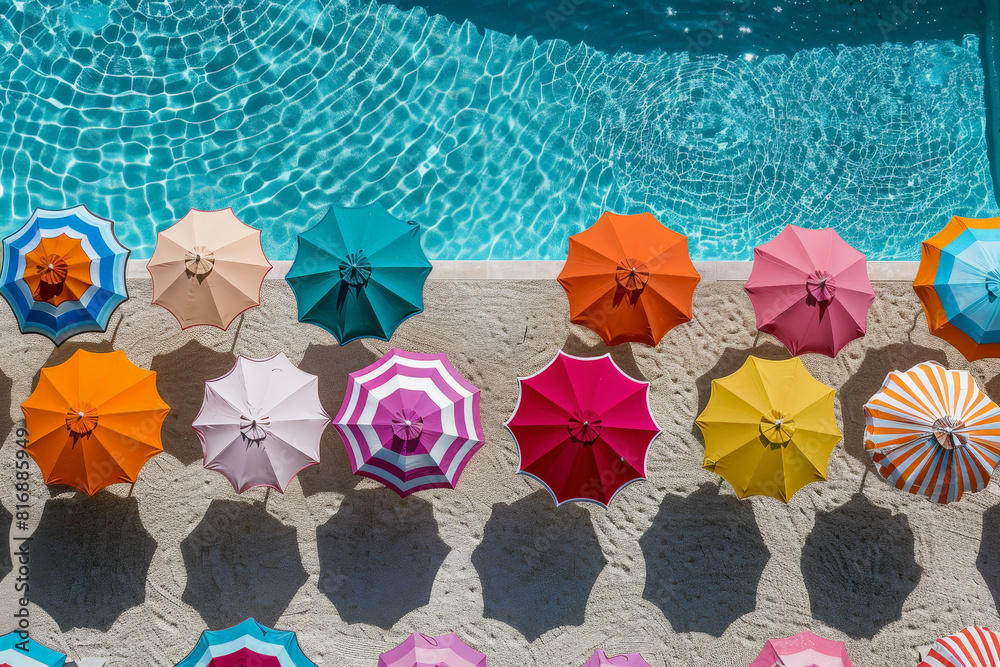 Poster Multiple bright umbrellas are neatly lined up alongside a swimming pool, adding a vibrant touch to the poolside environment