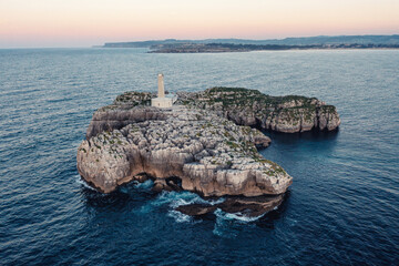 Small lighthouse on a stone rock in sea near the coast