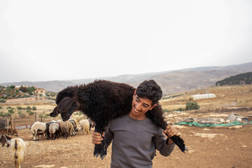young arabian teenager holding small sheep feeling happy and thanking God for his givings in desert