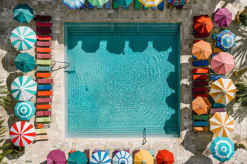 Aerial perspective showcasing a pool surrounded by vibrant, colorful umbrellas providing shade for swimmers and sunbathers
