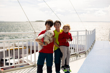 Children, experience ride with ferry on a fjord, strong wind on the deck of the ferry on sunny day