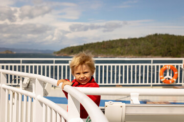 Children, experience ride with ferry on a fjord, strong wind on the deck of the ferry on sunny day