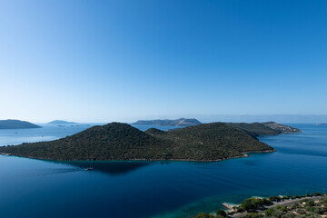 View from the Turkish city of Kas to the nearest island covered with pine forest and a beach with turquoise water and a pier