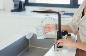 woman drinking water in her kitchen