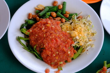 Plecing kangkung is a typical Indonesian dish originating from Bali and Lombok. Plecing kangkung consists of boiled water spinach and served cold and fresh with tomato sauce, cayenne pepper, salt. 