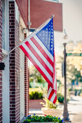 An American flag is hanging from a building on a traditional street in a small town.