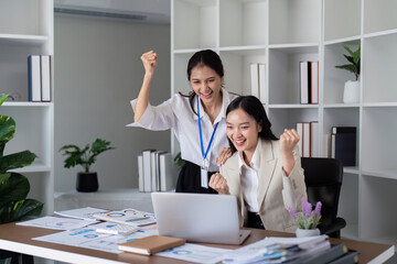 Happy businesswomen celebrating success in a modern office. Concept of teamwork, achievement, and corporate victory