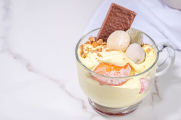 Mochi parfait trendy asian dessert, ice cream parfait layered with fruit, berry, sweets and various mochi. Summer frozen sweet snack in portioned cup, copy space