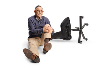 Mature man falling froma chair holding his painful knee and sitting on the ground