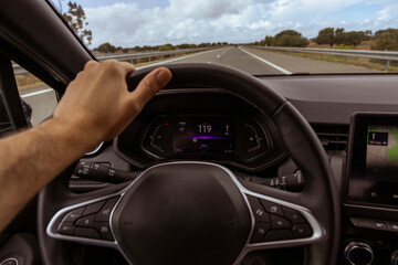 Fototapeta premium Driver view to the speedometer at 119 kmh, on a road blurred. Daylight view from inside a car of driver POV of the road landscape.