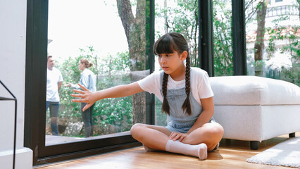 Stressed and unhappy young girl huddle in corner, cover her ears blocking sound of her parent...