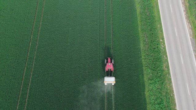 Increasing wheat yields using fertilizers. Tractor spreading agricultural lime in field aerial view