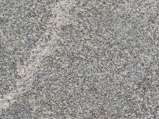 Granite texture. Natural gray granite with a grainy pattern. Stone background. Solid rough surface of rock. Durable construction and decoration material. Close-up.