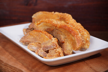 Thai food. Crispy fried pork belly cut into pieces on a wooden table.